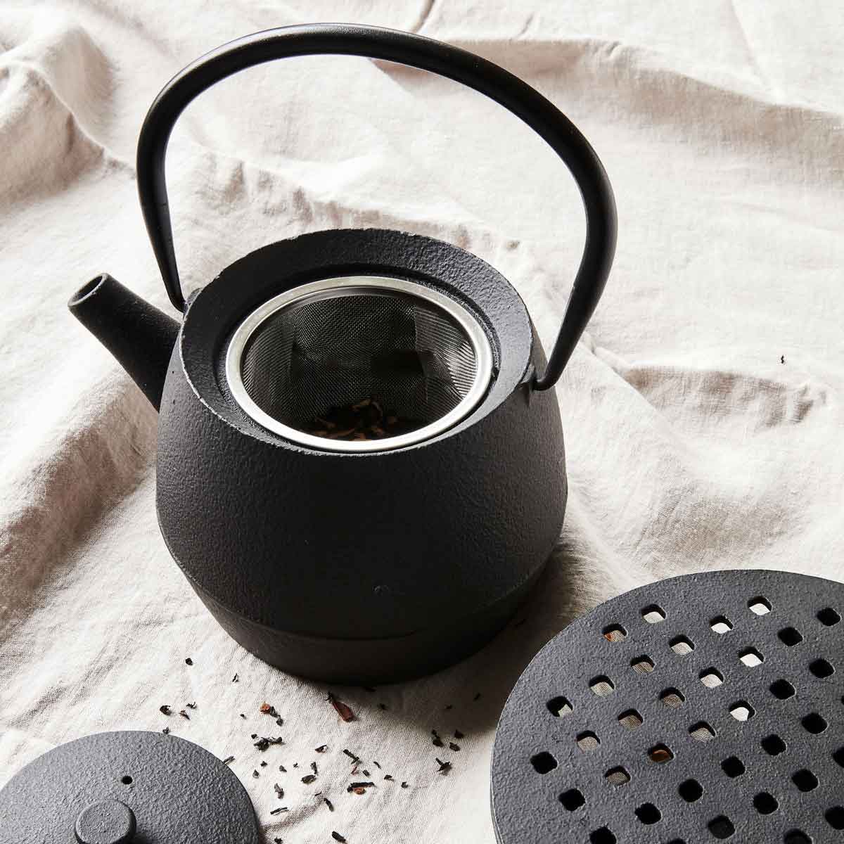Schwarze Teekanne mit Henkel und Teesieb - Ansicht von Oben mit geöffneter Kanne