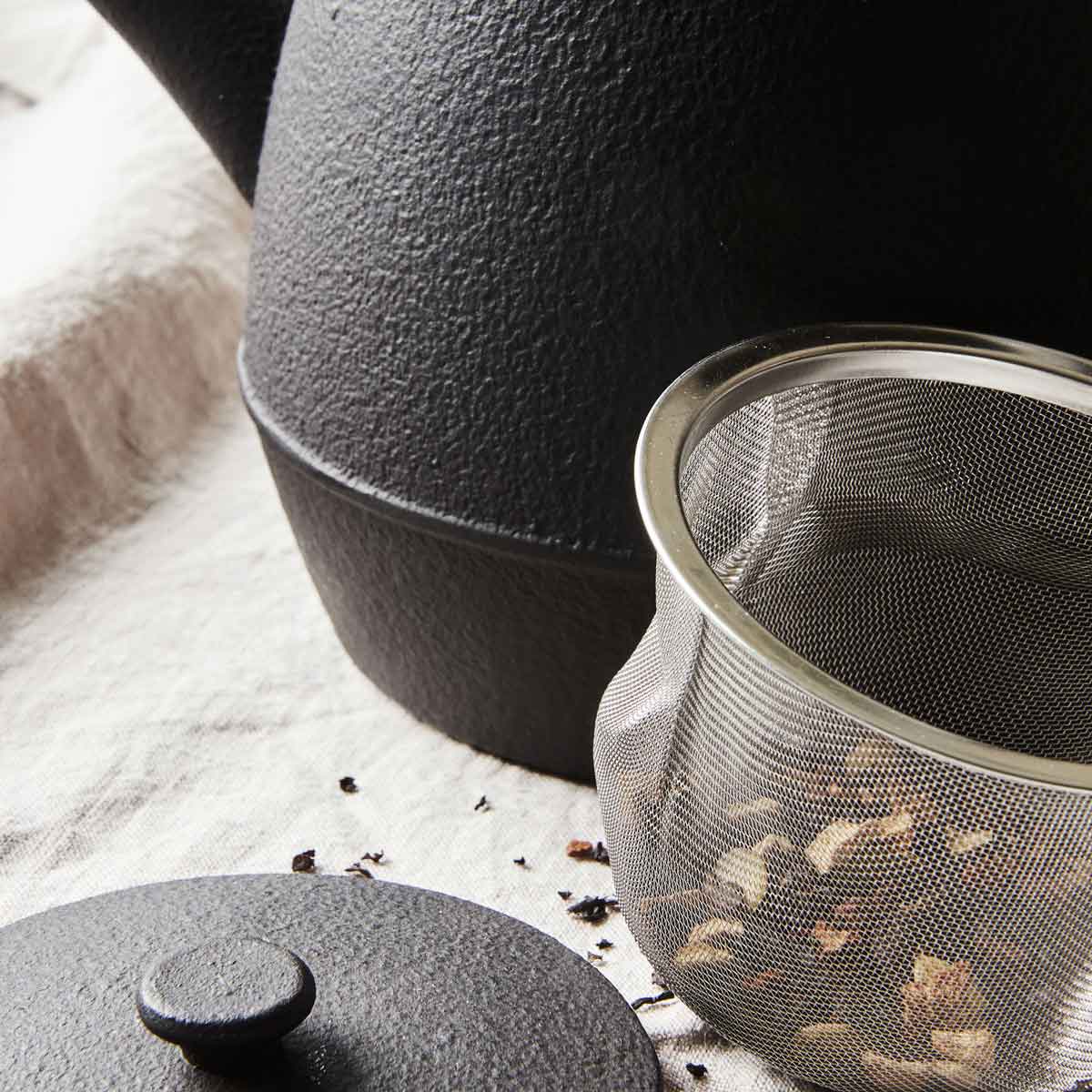 Schwarze Teekanne mit Henkel und Teesieb - Detailansicht und Teesieb
