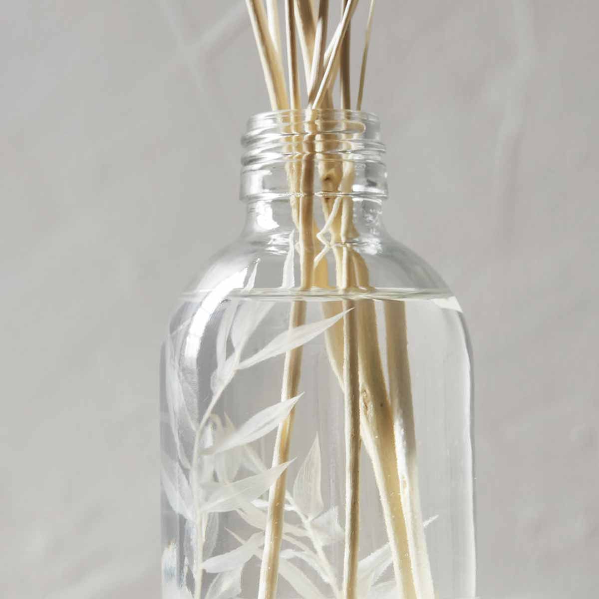 Diffuser_Timber_haze_309860034_4 Raumduft Timber haze mit Flakon aus Klarglas - Nahaufnahme der Flasche mit den Rattanstäben